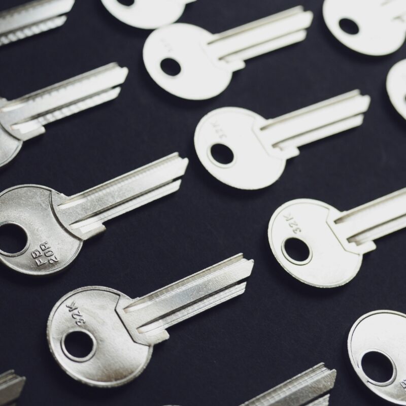 Close-up of multiple silver house keys arranged on a dark surface.